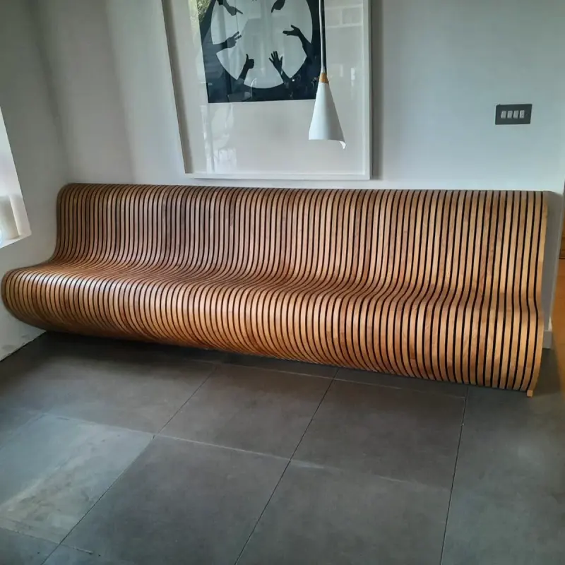 Long sculpted bench made from stacked timber slats