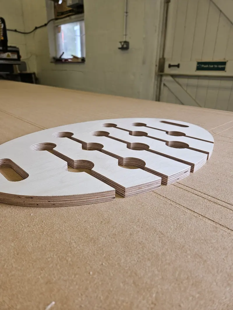 Oval plywood rack with keyhole slots on the CNC bed