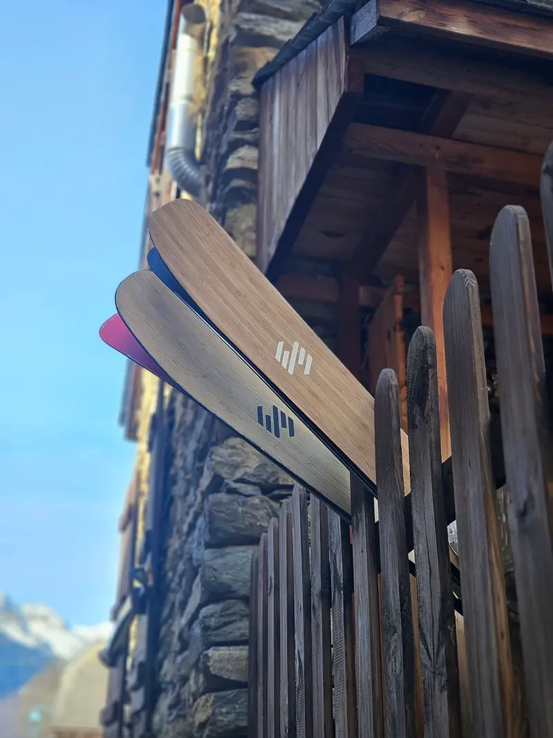 Pair of wood-topped skis leaning on a chalet balcony in the mountains